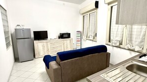 Cocina compacta con refrigerador, microondas y pileta.