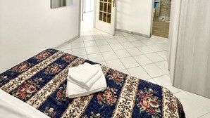Un dormitorio con cama, espejo, equipo de aire acondicionado y una puerta que da a otra habitación.