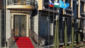 The exterior of the Mantra Hotel with a grand entrance, a red carpeted staircase, and multiple flags. - Manifa Hotel (Tashkent)