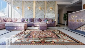 A modern lobby with a marble reception desk, plush seating, and a decorative carpet. - Manifa Hotel (Tashkent)