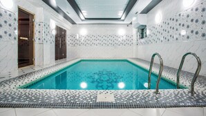 A modern indoor swimming pool with a tiled floor and walls, a skylight ceiling, and a clear blue pool. - Manifa Hotel (Tashkent)