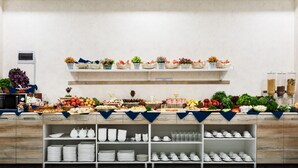 A buffet setup with various food items and a selection of white dishes and cups. - Manifa Hotel (Tashkent)