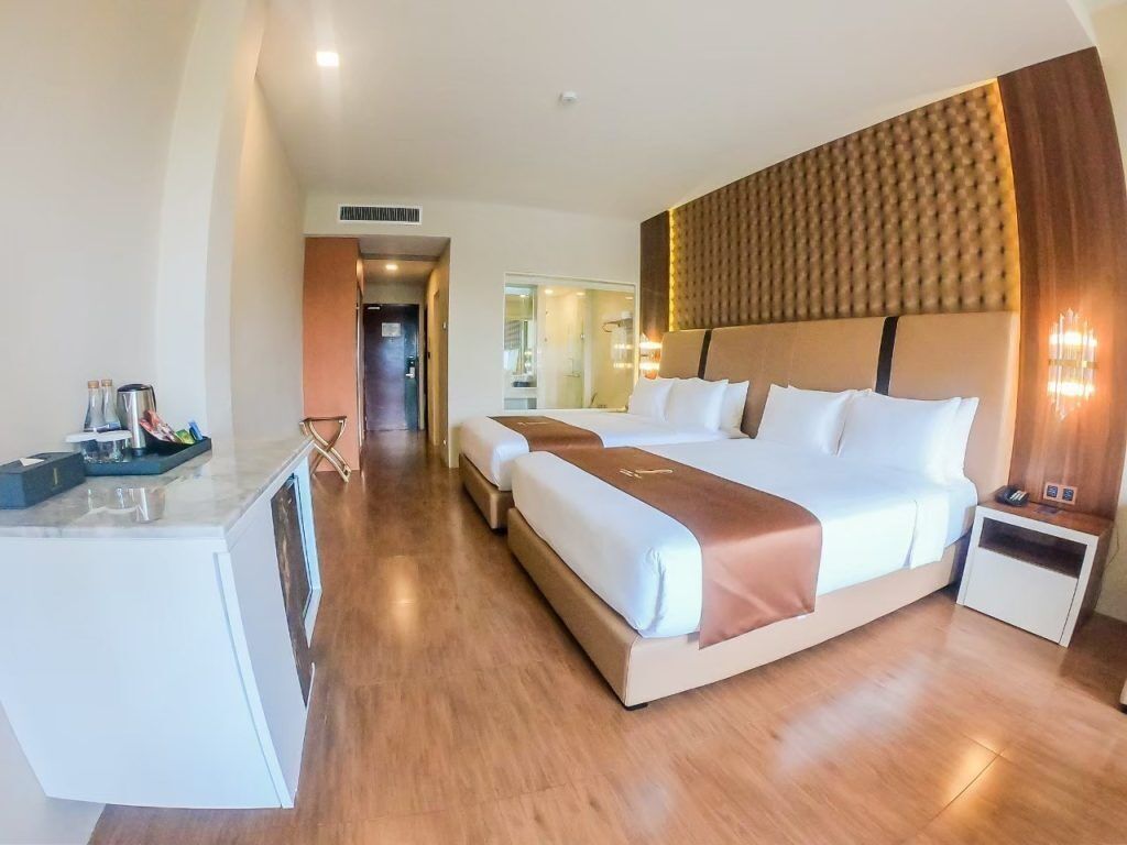 Habitación de hotel con una cama grande, una mesita de noche, un escritorio con silla y un baño visible a través de una puerta abierta.