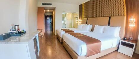 Habitación de hotel con una cama grande, una mesita de noche, un escritorio con silla y un baño visible a través de una puerta abierta.