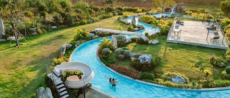 Una piscina con tobogán, rodeada de abundante vegetación y una vista panorámica de colinas.