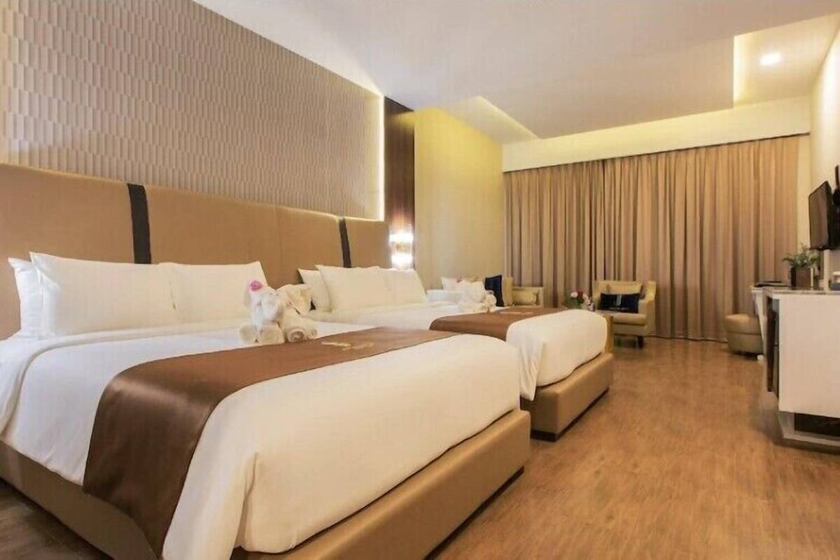 Ein Hotelzimmer mit einem großen Bett, einem kleineren Bett, einem Schreibtisch und einem Stuhl.