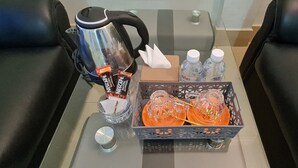 A table with a coffee maker, napkins, bottled water, and a box of orange juice. - Chan&Both guesthouse (Sihanoukville)