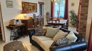 Una sala de estar acogedora con un sofá de cuero negro, una mesa de centro de madera y un comedor con mesa y sillas.