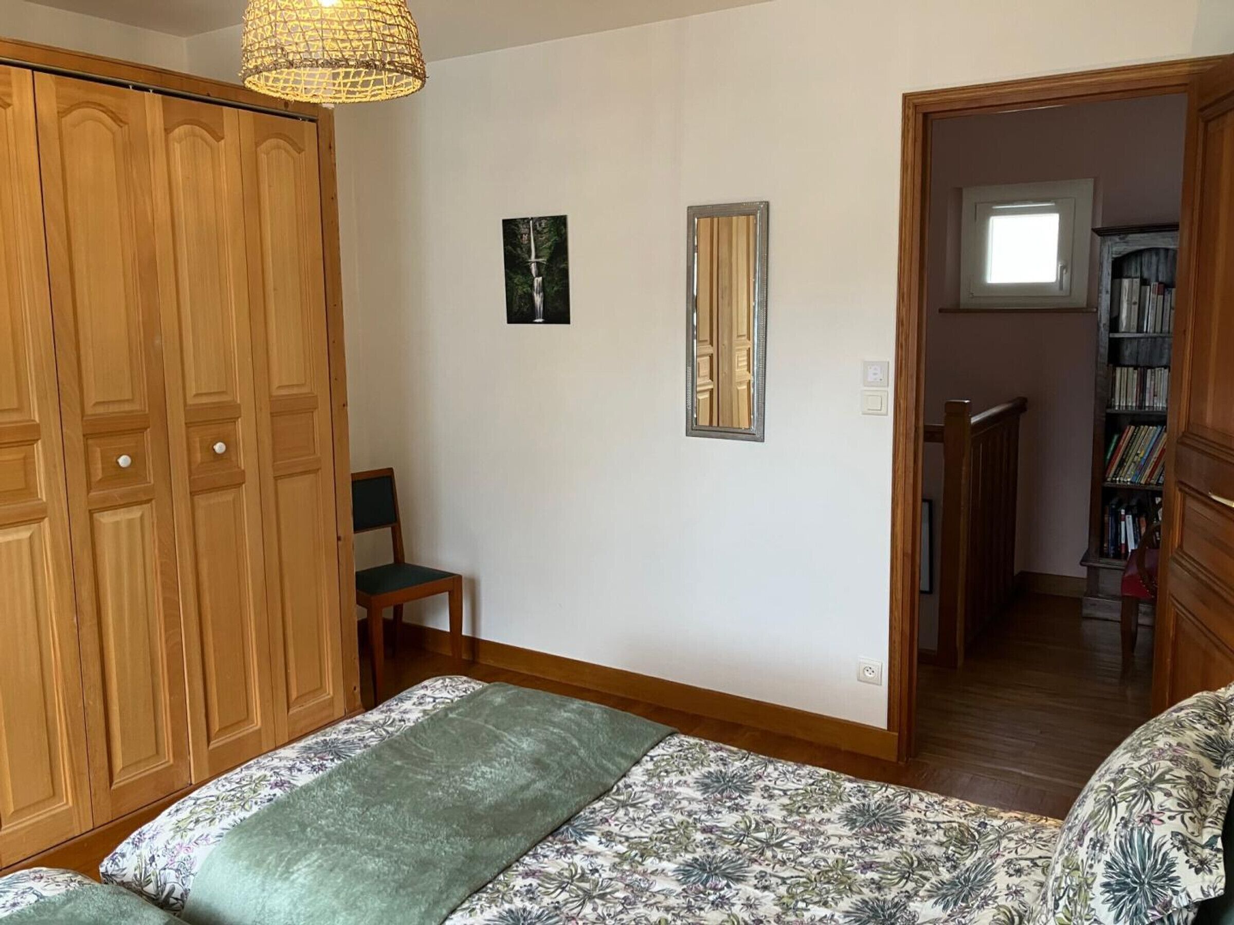 Un dormitorio con cama, una silla, un armario y una estantería.