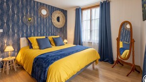 Un dormitorio con cama, mesita de noche, lámpara, espejo y ventana con cortinas.