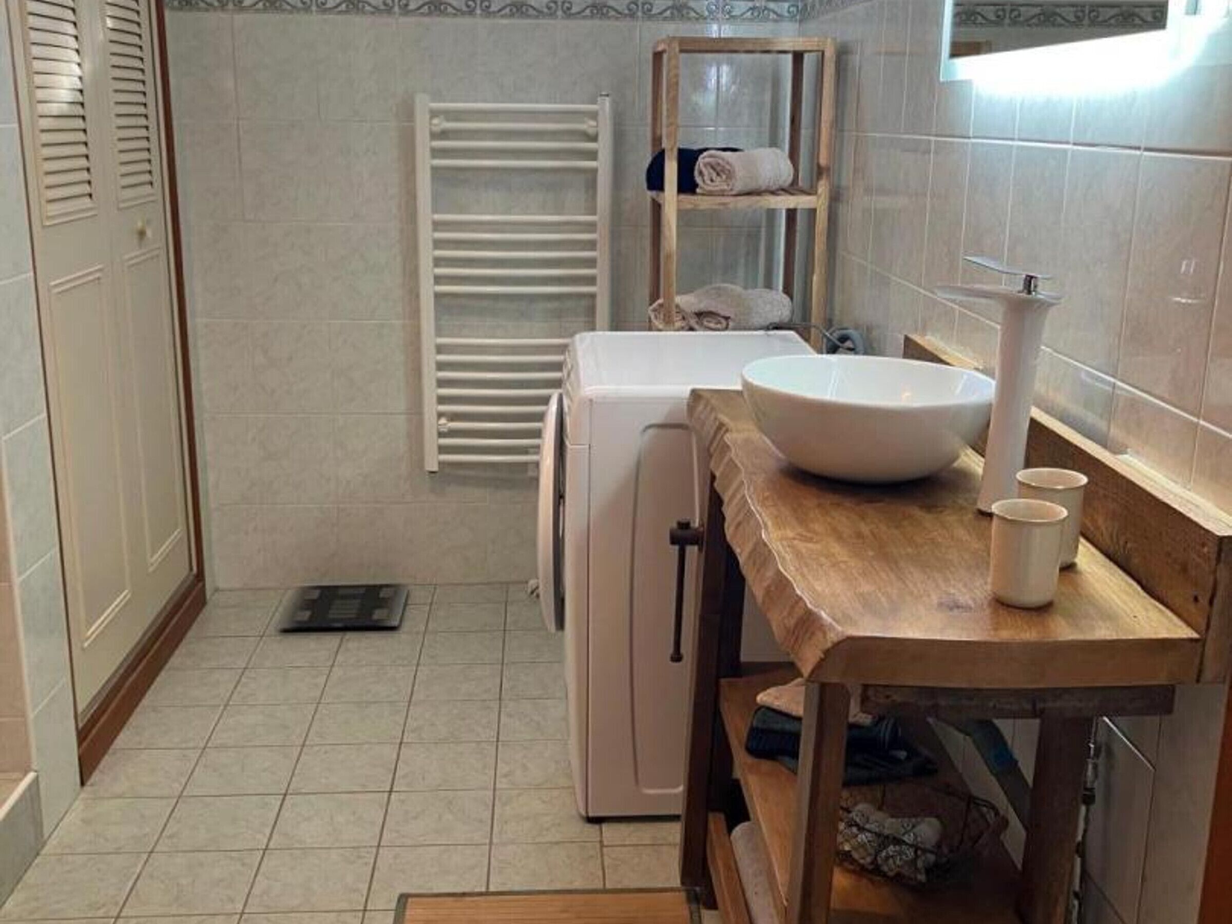 Un bagno con lavandino, specchio, porta asciugamani e una piccola mensola.