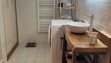 Un bagno con lavandino, specchio, porta asciugamani e una piccola mensola.
