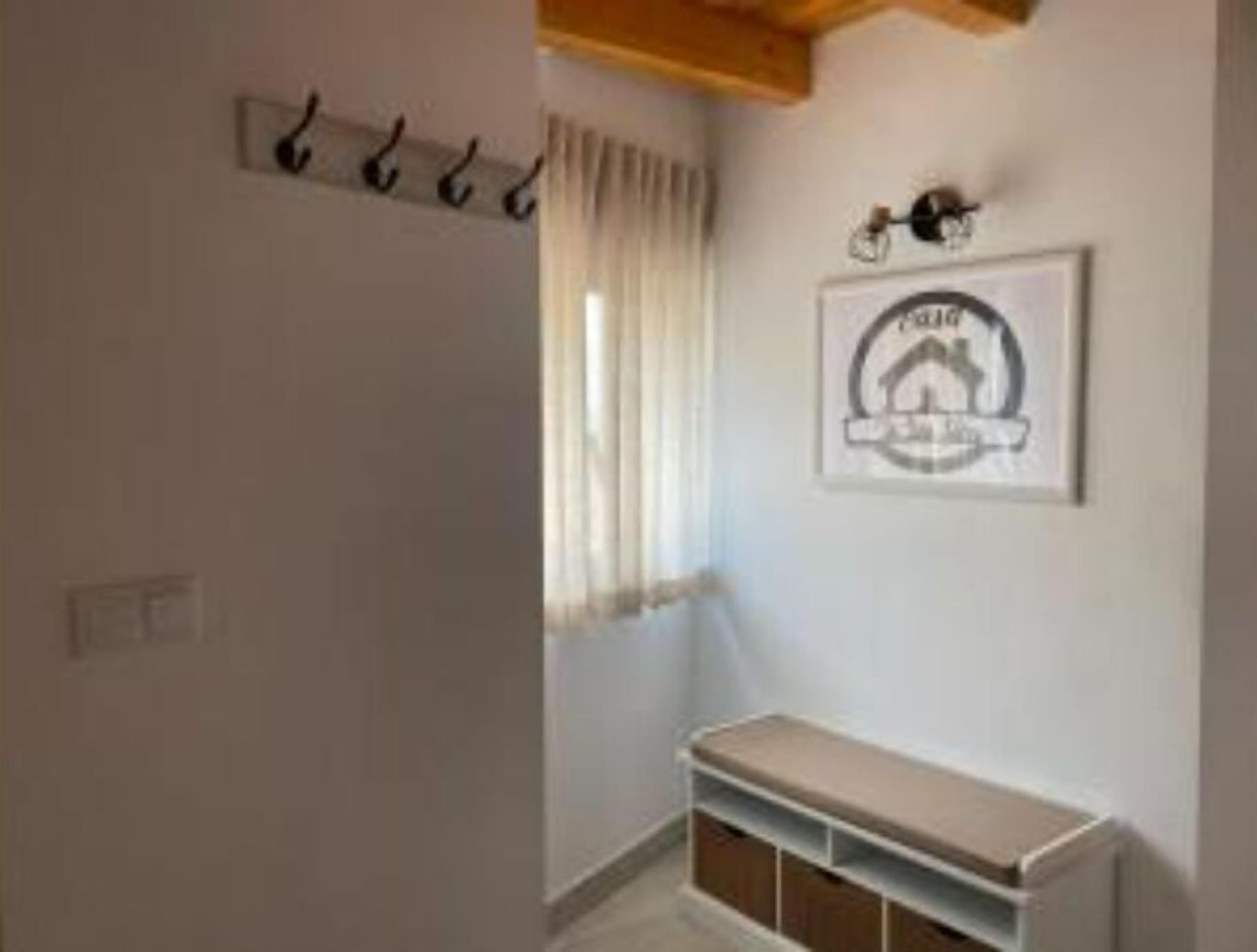 Ein Zimmer mit einer Bank, einem Kleiderhaken und einem gerahmten Logo an der Wand.