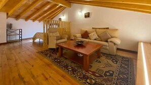 Ein gemütliches Wohnzimmer mit Holzboden, einer Sofagarnitur, einem Couchtisch und einem gemusterten Teppich.