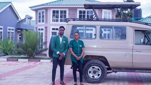 A beige SUV parked in front of a building with a green roof and a paved area with red and gray tiles. - LA'TONNA SAFARI HOTEL (Serengeti)