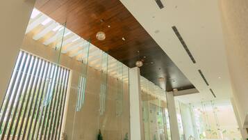 A modern lobby with glass partitions, wooden ceiling, and indoor plants.