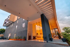 Un bâtiment moderne doté d’une grande entrée, de plantes en pot et surplombant un ciel dégagé.
