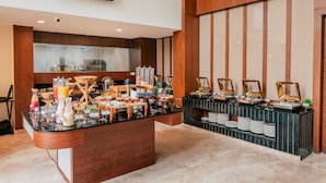 Un buffet proposant une variété de plats et de boissons, un téléviseur fixé au mur et un décor mural en panneaux de bois.