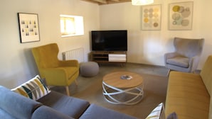 Ein Wohnzimmer mit einer Couch, Sesseln, einem Fernseher und Kunstwerken an den Wänden.