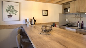 Eine Holz-Küche mit Kaffeemaschine, Wasserkocher und einem Drahtkorb auf der Arbeitsfläche.