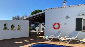 A swimming pool with lounge chairs, a lifebuoy, and a covered patio area.