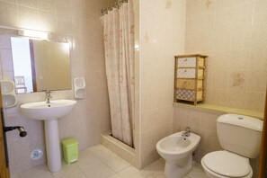 A bathroom with a pedestal sink, a bidet, a toilet, a shower curtain, and a small cabinet with drawers. - Charming 2-Bedroom Apartment 100m from the Beach Terrace Fiber WiFi  (Linguizzetta)