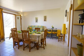 A dining area with a table set for four, wooden chairs, a yellow tablecloth, and a yellow lamp. - Charming 2-Bedroom Apartment 100m from the Beach Terrace Fiber WiFi  (Linguizzetta)