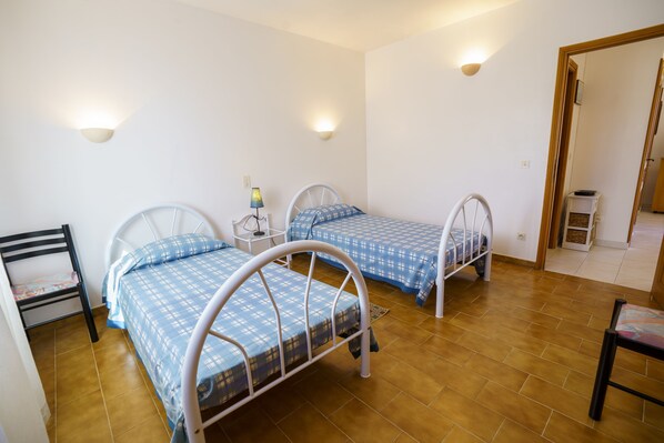 A room with two metal bunk beds, a small bedside table with a lamp, and a chair. - Charming 2-Bedroom Apartment 100m from the Beach Terrace Fiber WiFi  (Linguizzetta)