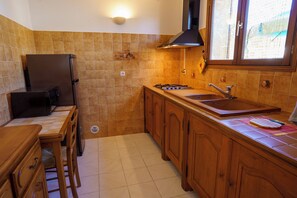 Une cuisine de taille réduite, équipée d’un réfrigérateur, d’une cuisinière, d’un évier et de meubles de rangement en bois.