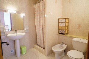 A bathroom with a pedestal sink, a bidet, a toilet, a shower curtain, and a small cabinet with drawers. - Charming 2-Bedroom Apartment 100m from the Beach Terrace Fiber WiFi  (Linguizzetta)