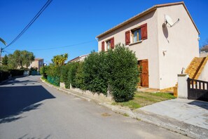 A residential street with a house featuring a red door, a satellite dish, and a staircase leading to the entrance. - Charming 2-Bedroom Apartment 100m from the Beach Terrace Fiber WiFi  (Linguizzetta)