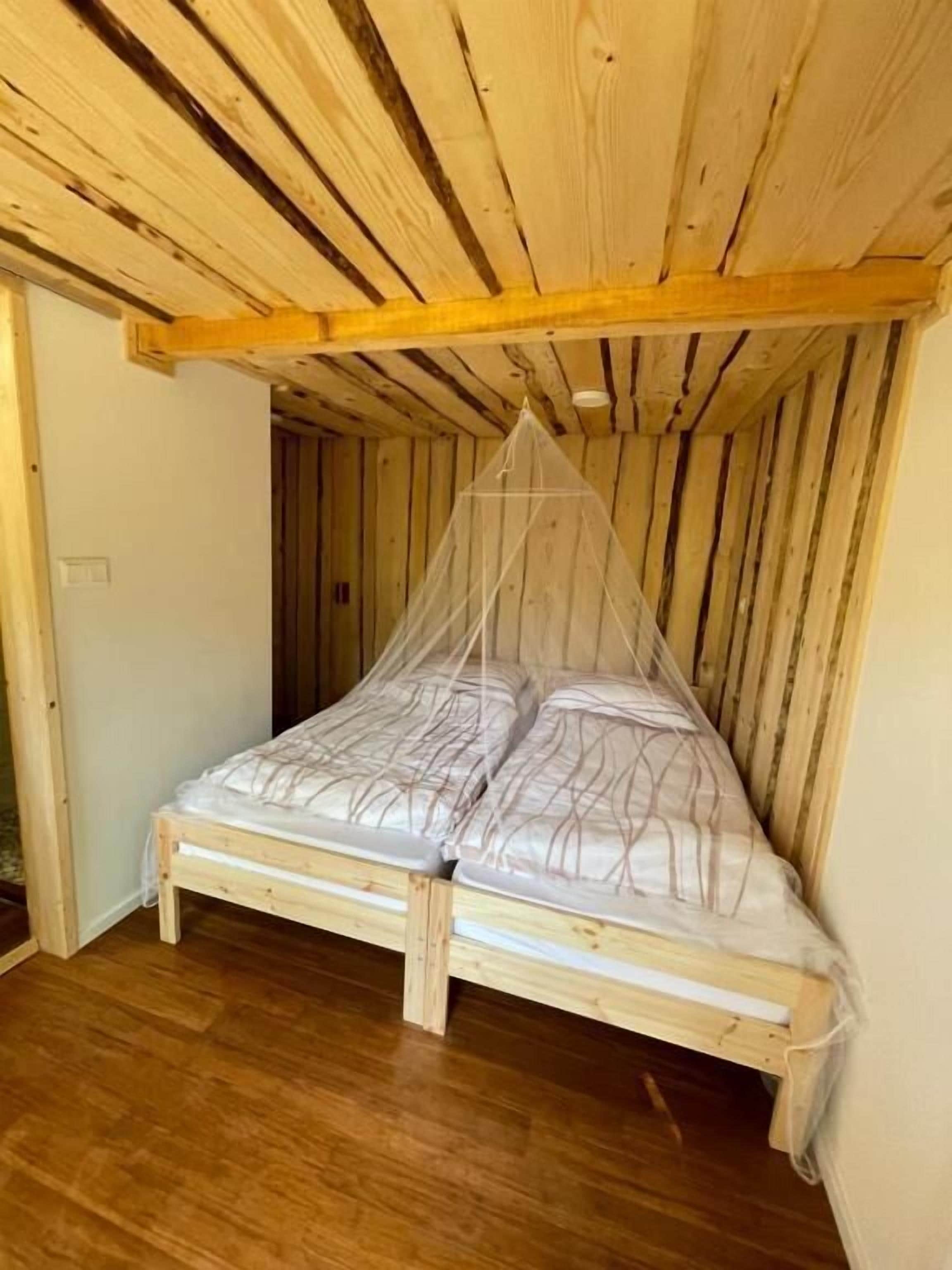 A wooden loft bedroom with a bed under a mosquito net.