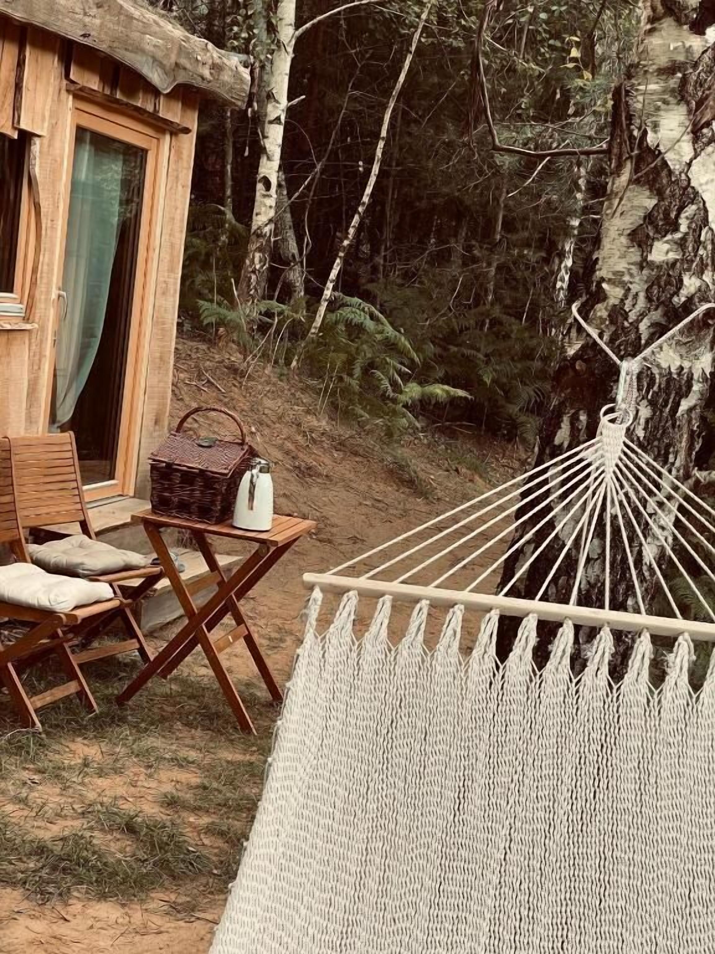 Eine Holzhütte mit einer Hängematte, einem Tisch mit einem Korb und einem Stuhl.