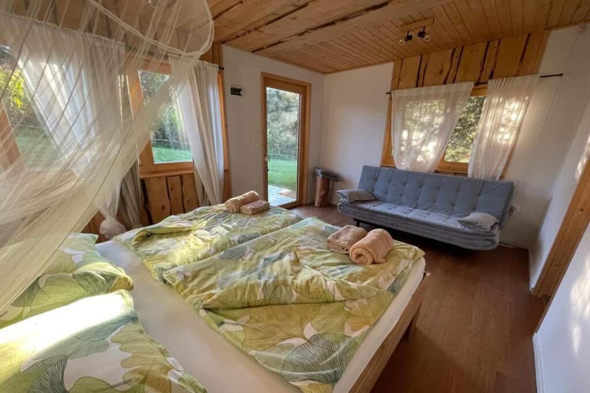 A bedroom with a bed, a sofa, and a window.