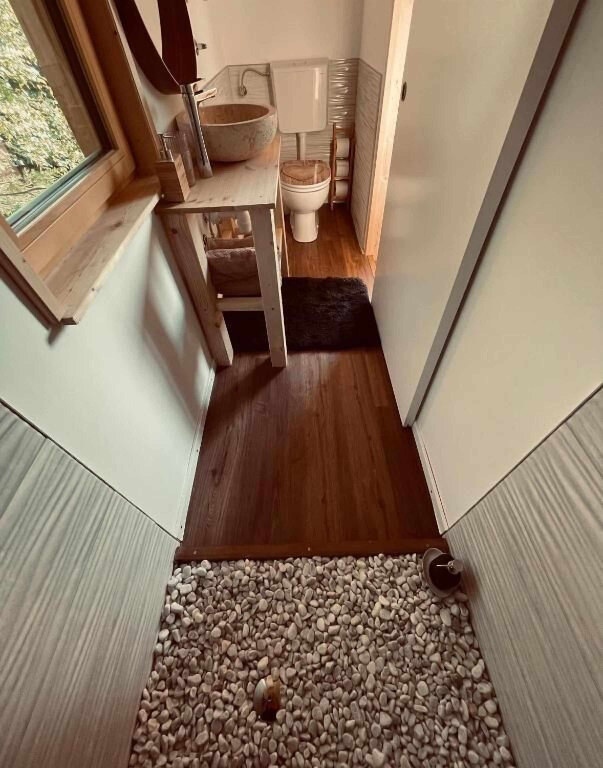 A compact bathroom with a wooden vanity, a large sink, and a toilet.