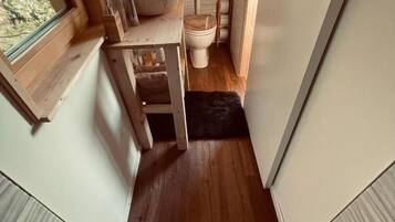 A compact bathroom with a wooden vanity, a large sink, and a toilet.