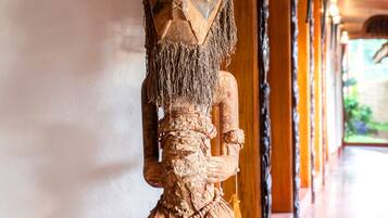 A wooden statue in a corridor with a tiled floor and a wooden ceiling.