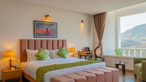 Une chambre d’hôtel avec un grand lit, un bureau, une chaise, une lampe et une vue sur l’extérieur.