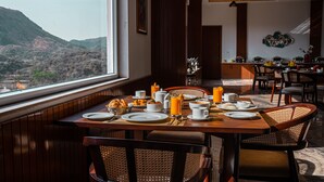 Un coin repas avec une table dressée pour le petit-déjeuner, une vue sur les montagnes et un aménagement intérieur moderne.