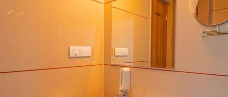 A modern bathroom with a white sink, wooden cabinet, and a mirror.
