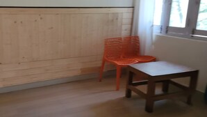 Et værelse med trægulv, et træbord og en orange stol.