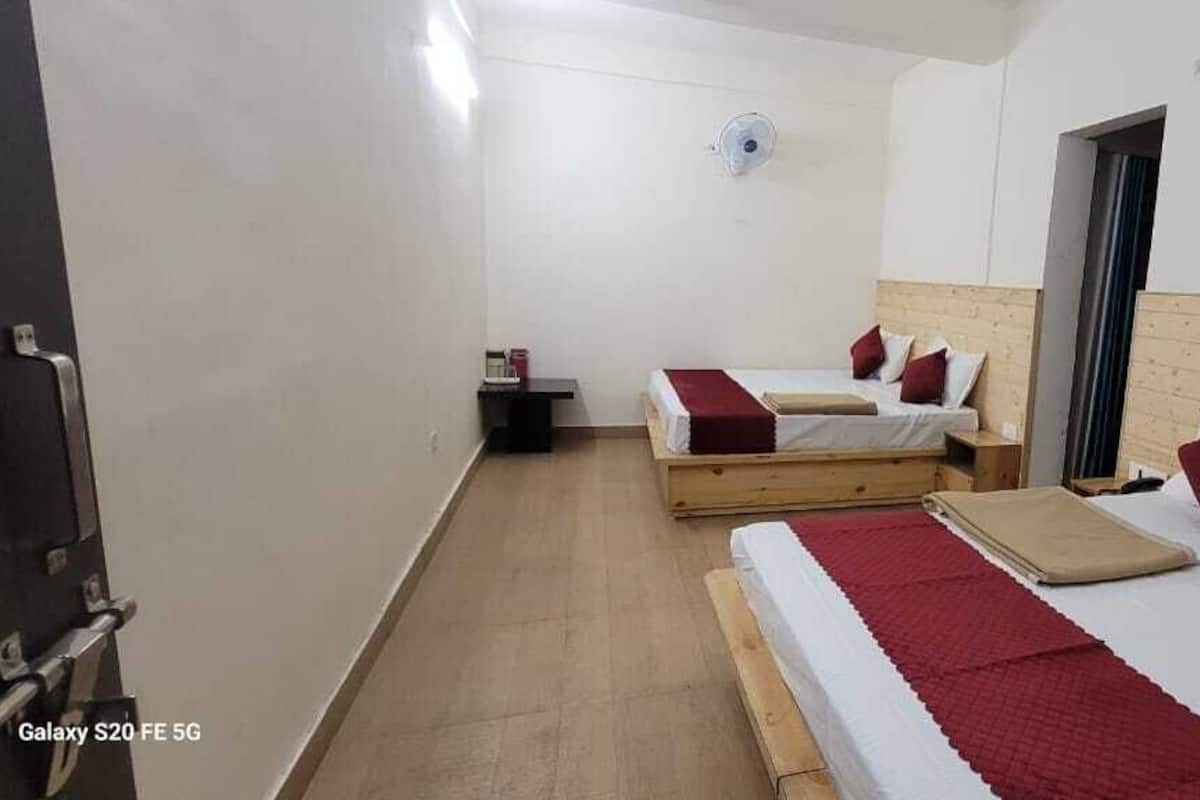 A hotel room with two beds, wooden headboards, and a small bedside table.