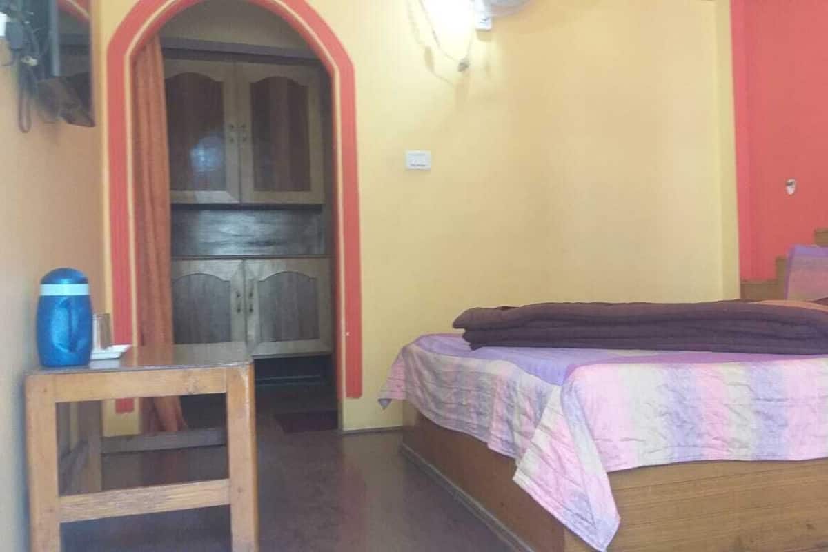 A bedroom with a bed, a wooden headboard, a small table, and a door leading to another room.