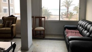 Un salon avec vue sur la plage, comprenant un canapé, un fauteuil et une table.