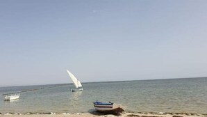 Une mer calme avec un voilier et un petit bateau ancré près du rivage.