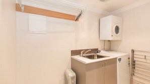 A compact kitchen with a sink, a built-in oven, and a wall-mounted washing machine.