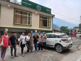 Un grupo de personas de pie frente a un edificio con un letrero que dice 'Harela Inn Hotel and Restaurant'.