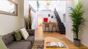 Ein modernes Wohnzimmer mit Sofa, Couchtisch und einer Treppe, die in einen Küchenbereich führt.