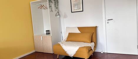 A bedroom with a bed, a wardrobe, a mirror, and a framed artwork on the wall.