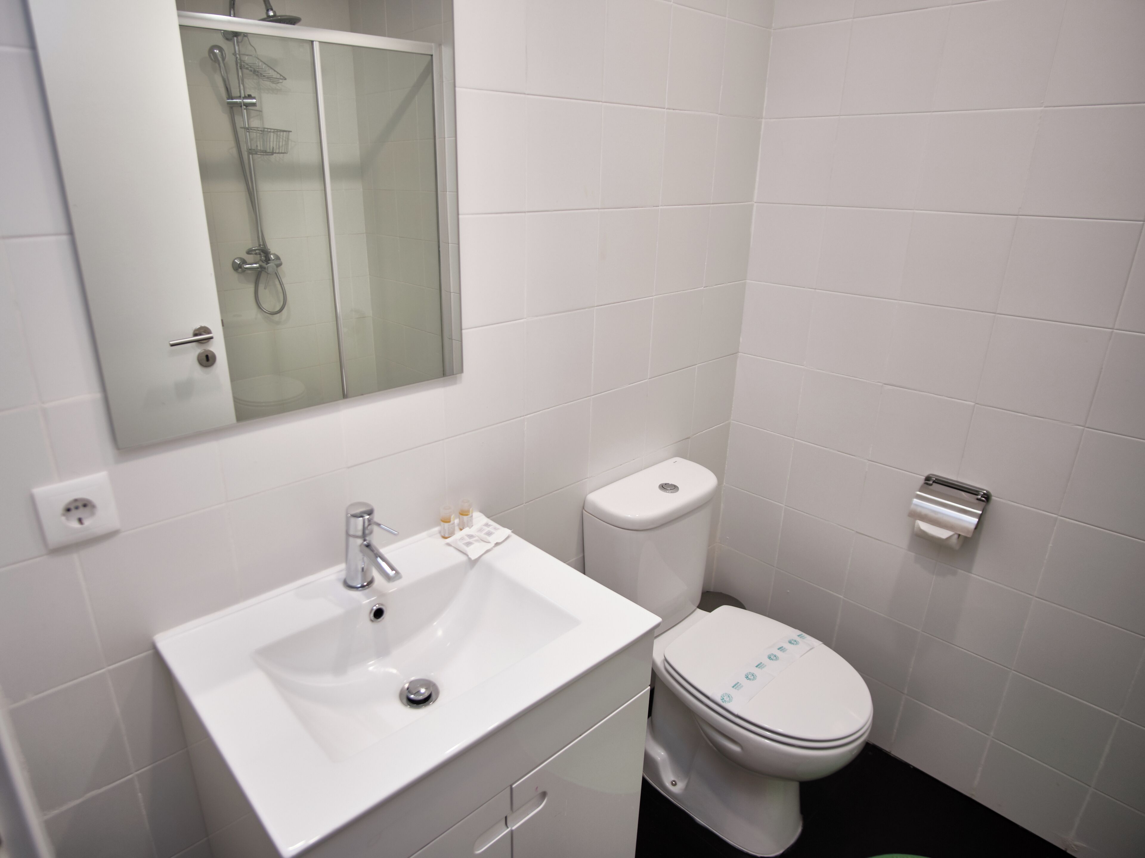 A bathroom with a white sink, toilet, and shower.